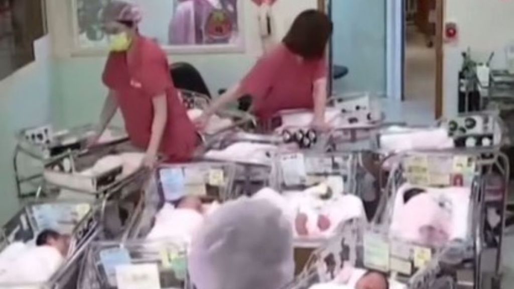 Image shows a hospital nursery during an earthquake. Staff members are holding the bassinets to keep them from rolling.