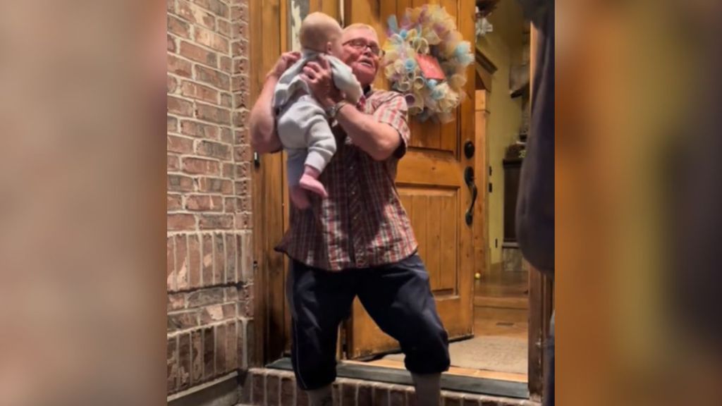 A grandpa picks up his baby grandson on the stoop.