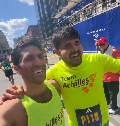 Nev Schulman and Francesco Magisano smile. They each have an arm around the other as they walk forward.