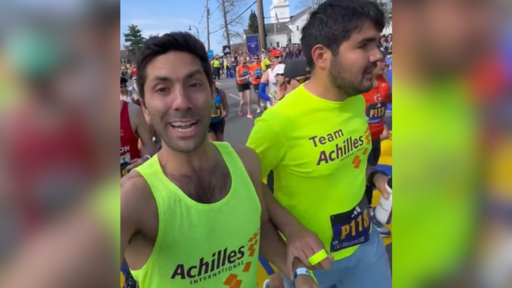 Nev Schulman smiles as him and a blind athlete run in the Boston Marathon