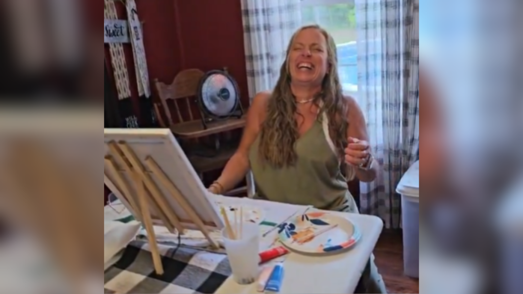 woman sitting at a table laughing with her head tilted back