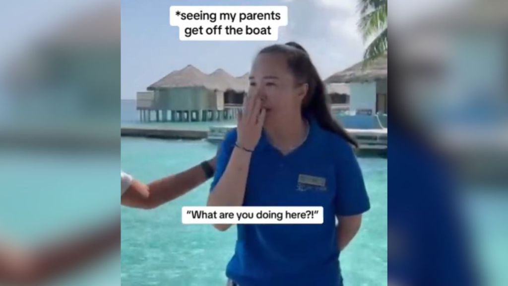 A daughter working in the Maldives covers her mouth in surprise.