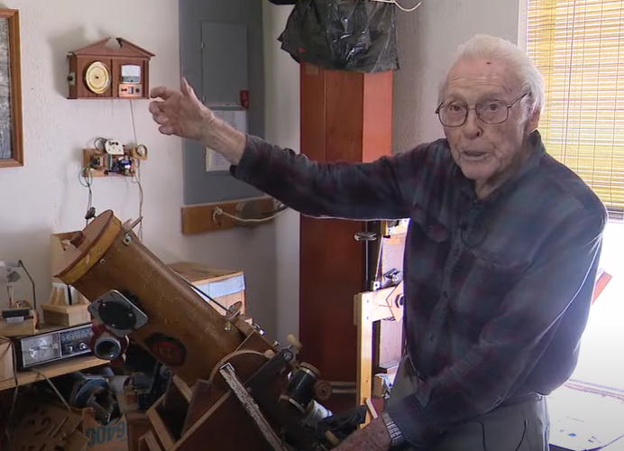 An elderly eclipse chaser shows off the telescope he built.
