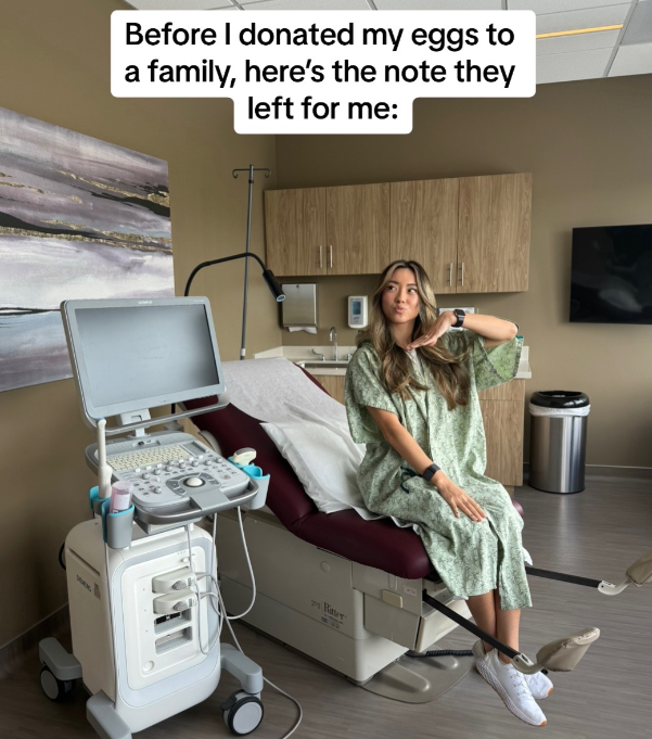 A young woman in a hospital gown sitting on an exam table.