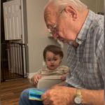 A great-grandpa reading out loud to a toddler.