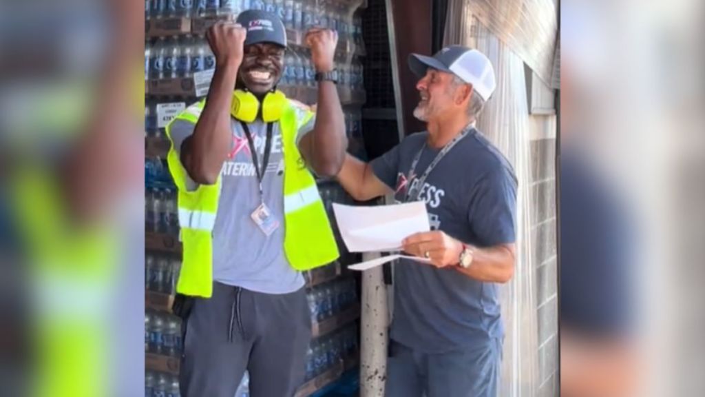 An employee raises his fists in excitement as his employer holds the letter granting him asylum.