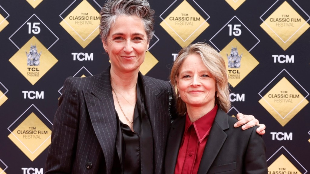 Alexandra Hedison smiles with an arm around her wife, Jodie Foster, at a ceremony outside of the TCL Chinese Theatre.