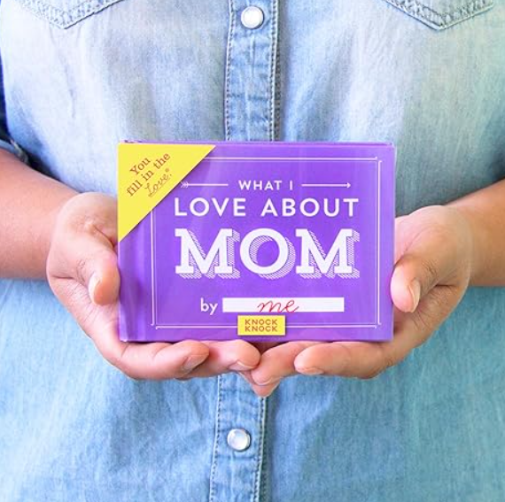 A person holding a "What I Love About Mom" book.