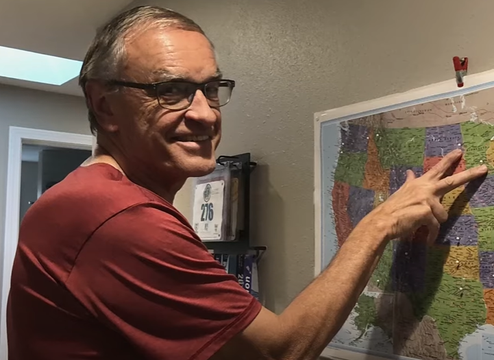 A man shows off a map of the United States with pins in it.