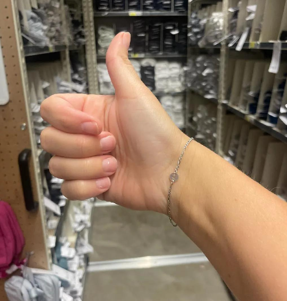 A person wearing a chain bracelet with a letter charm.