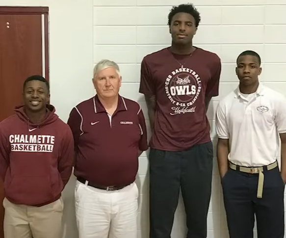 An old high school photo of Mitchell Robinson. He's posing with his high school basketball coach, Butch Stockton, and two others.