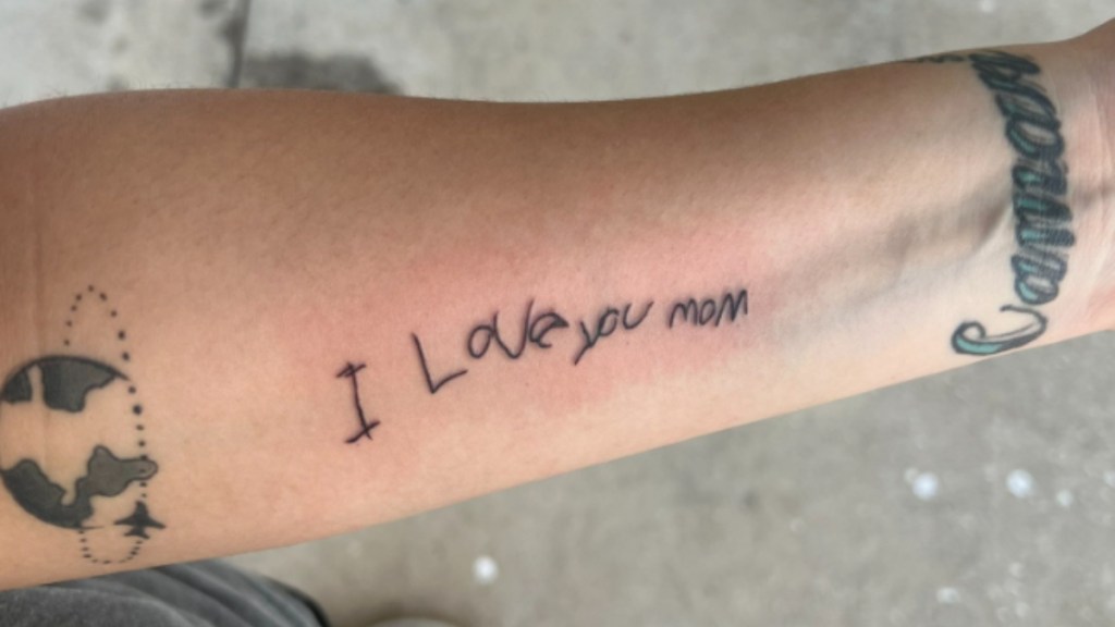 Close up of a woman's arm with a tattoo in her kid's handwriting that reads: I love you mom