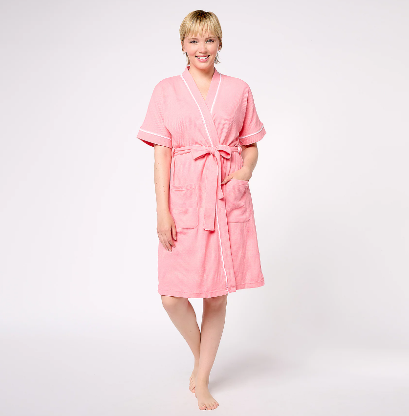 A blonde woman wearing a cozy pink robe.