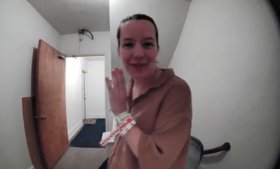A woman leans in to talk to a Ring doorbell camera.