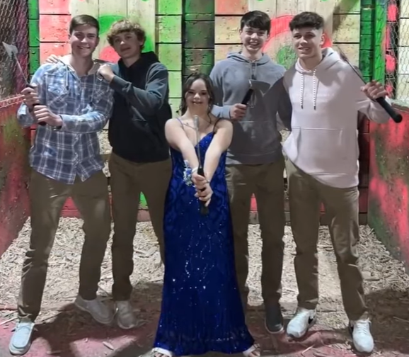 Four teen boys pose with axes as a teen girl named Annie poses in the center, dressed in a sparkly blue prom dress.