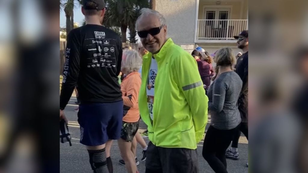 An elderly man wears a green jacket during a half marathon.