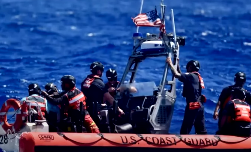 A group of rescuers stand on a U.S. Coast Guard small rescue ship.