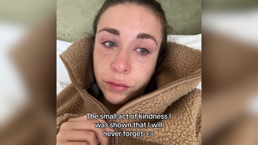 A woman with tears in her eyes looks into the distance. Text on the image reads: The small act of kindness I was shown that I will never forget