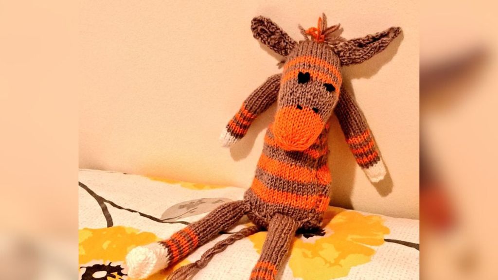 A handmade sock animal with a striped body.