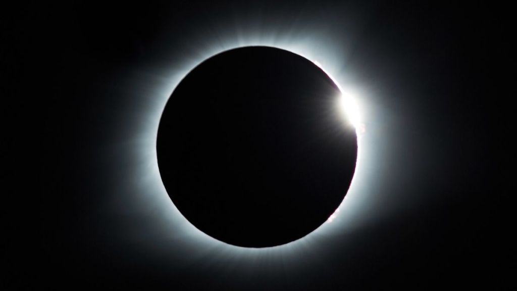 A total solar eclipse causing a ring of light in a dark sky.