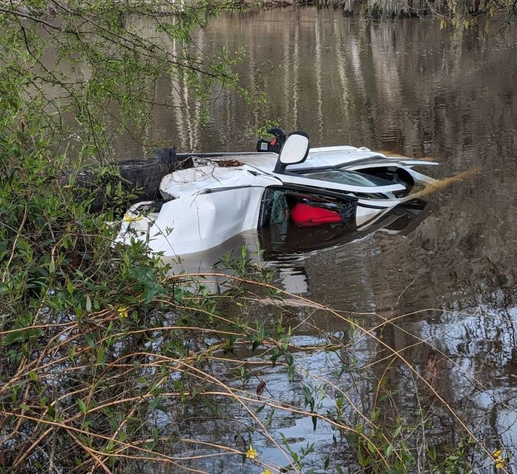 A white vehicle is half-submerged in water.