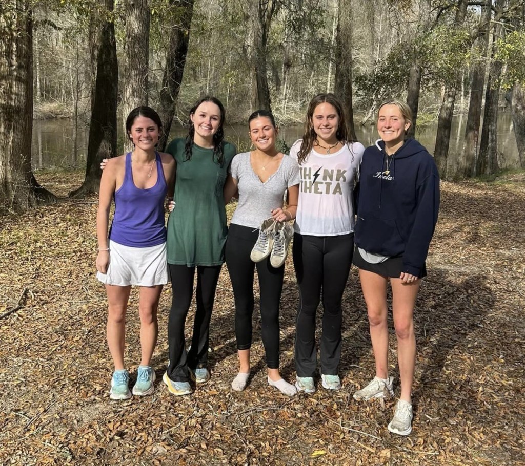 Five sorority sisters, Molly McCollum, Jane McArdle, Eleanor Cart, Clarke Jones and Kaitlyn Lannace, smile as they pose together outside in a wooded area.
