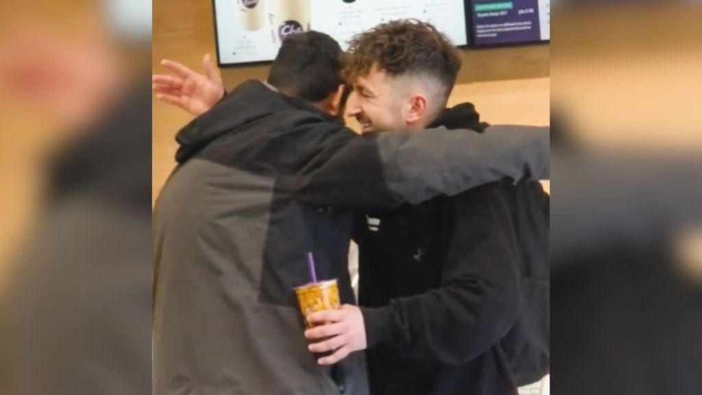Two strangers hugging in a coffee shop.