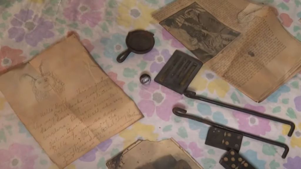 A time capsule with items like newspapers and a cast iron pan laid out.