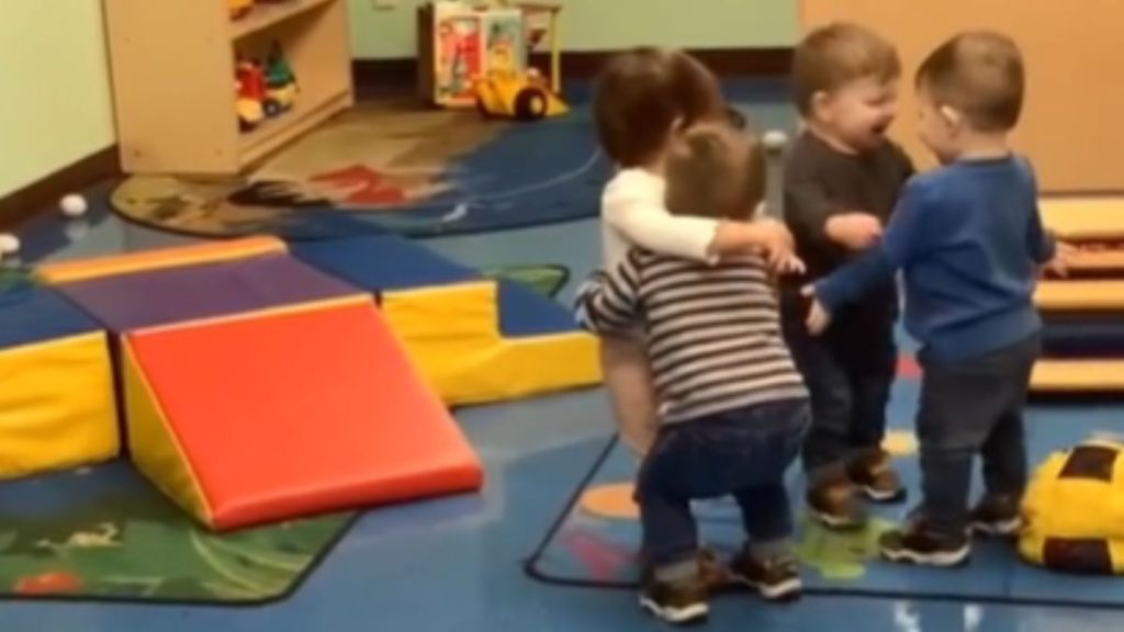 Four toddlers hug each other at a daycare center.