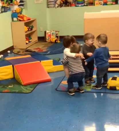 Four toddlers hug each other at a daycare center.