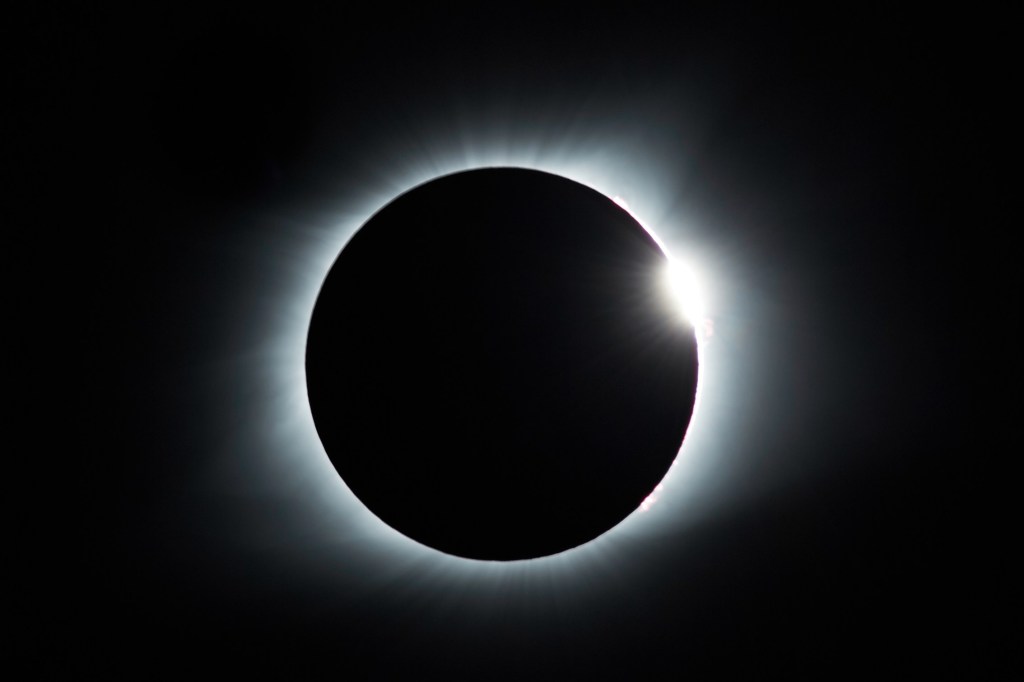 A total solar eclipse causing a ring of light in a dark sky. 