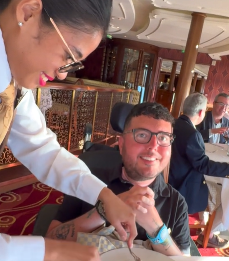 A waitress cuts up food for a diabled client on a Disney cruise.