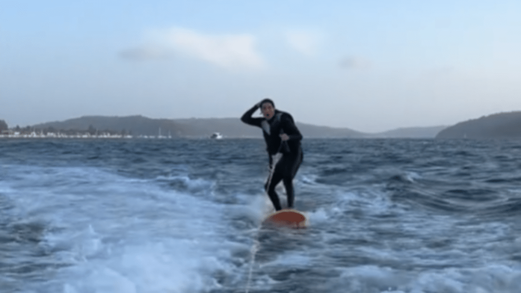 A person riding a wakeboard in the water and looking shocked