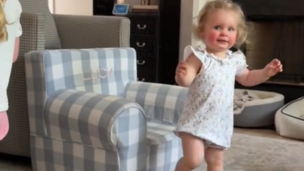 A toddler looks over at the camera as she starts to walk away from the toddler-sized chair she was sitting in.