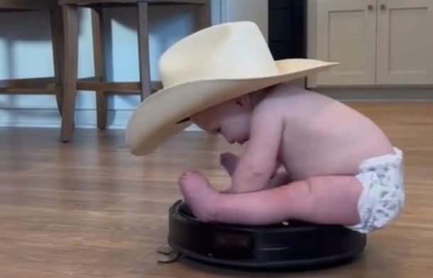 Image shows a diaper-wearing baby on a wild Roomba ride.