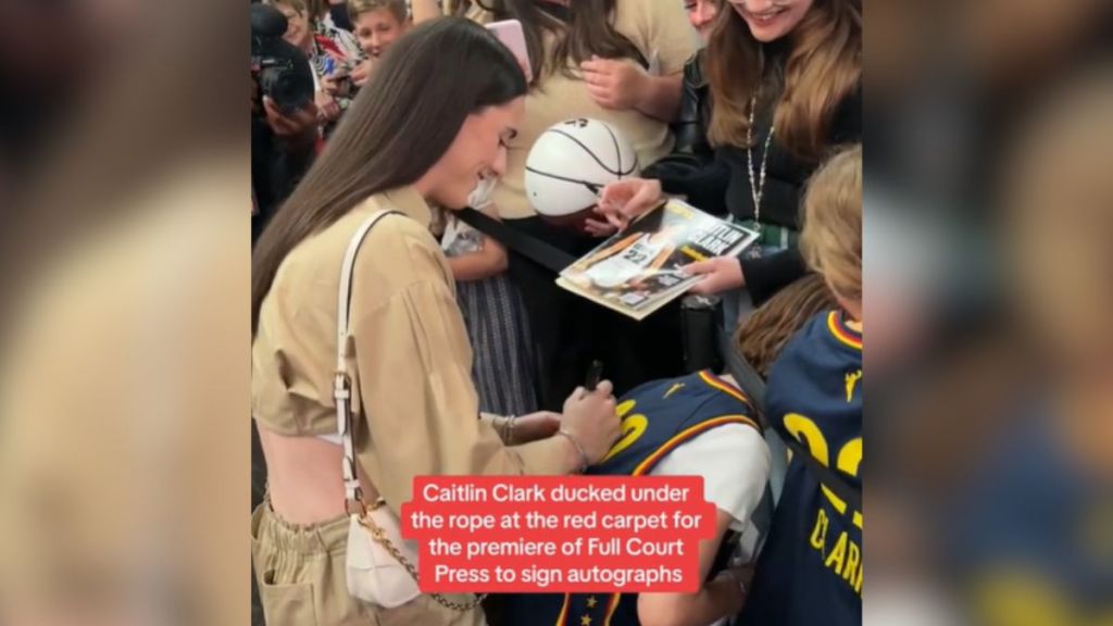 Celebrity athlete Caitlin Clark signing autographs at an event.