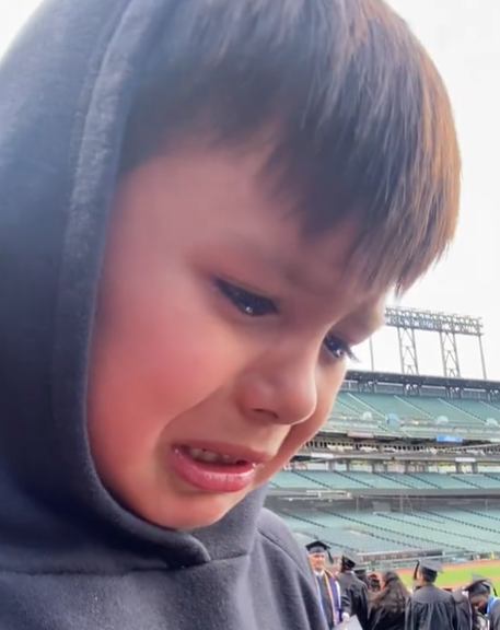 A little boy crying at his mom's graduation ceremony.