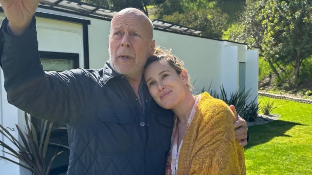Bruce Willis points toward the sky at something he's looking at while he rests an arm around his daughter, Rumer. Meanwhile, Rumer rests her head on Dad's shoulder. She smiles softly as she looks toward whatever he's showing her.