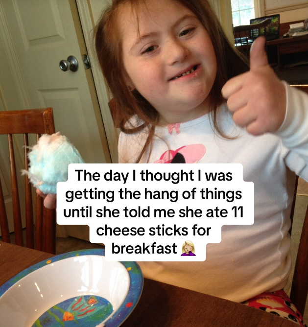 A young girl with Down syndrome giving a thumbs up.