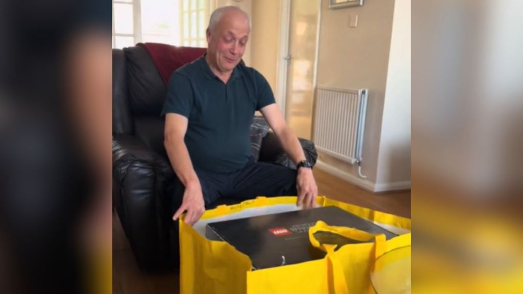 A dad is excited to open a yellow Lego bag.