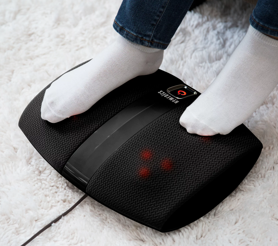 A person wearing white socks using a foot massager.