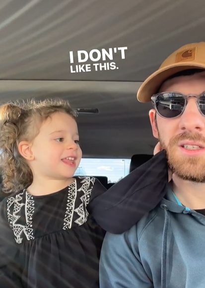 A little girl reaches out to touch her dad's beard.