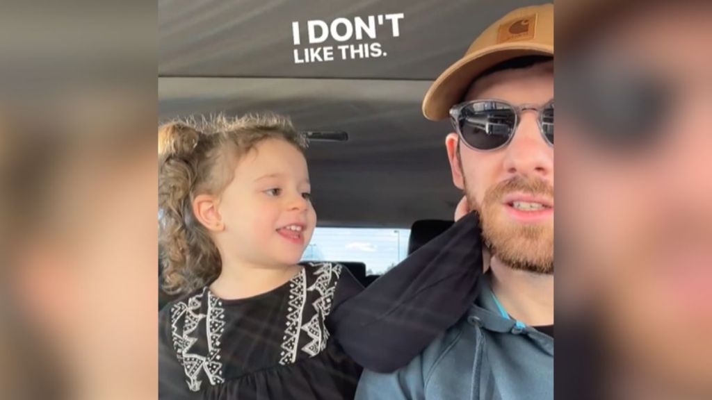 A little girl reaches out to touch her dad's beard.