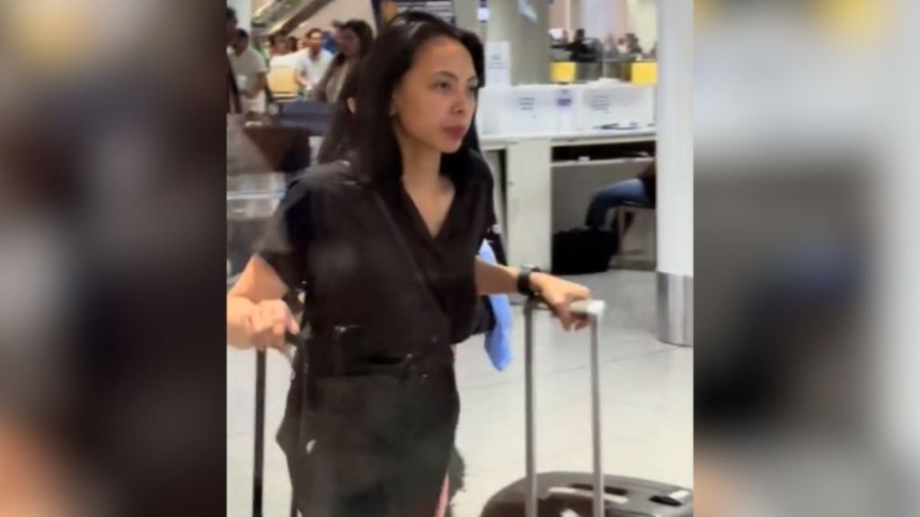 A woman walking through an airport looking annoyed and tired.