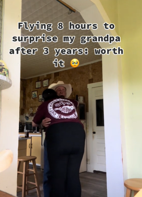 A grandfather in a cowboy hat hugs his granddaughter.