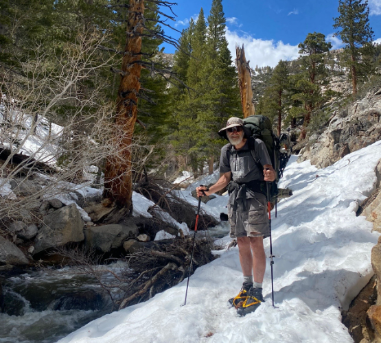 An elderly man hiking Mt. Whitney in the snow.