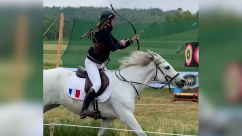 A young woman riding on horseback with a bow and arrow.