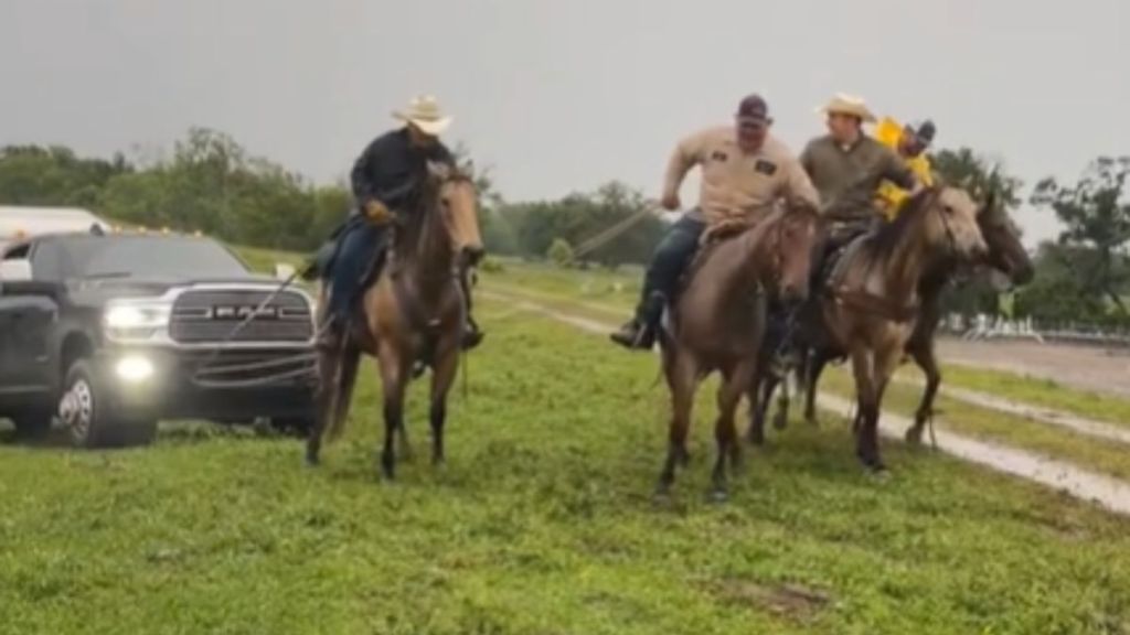 A group of cowboys on horses pulling a truck.