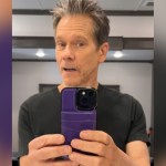 Kevin Bacon talks in front of a mirror, phone in hand