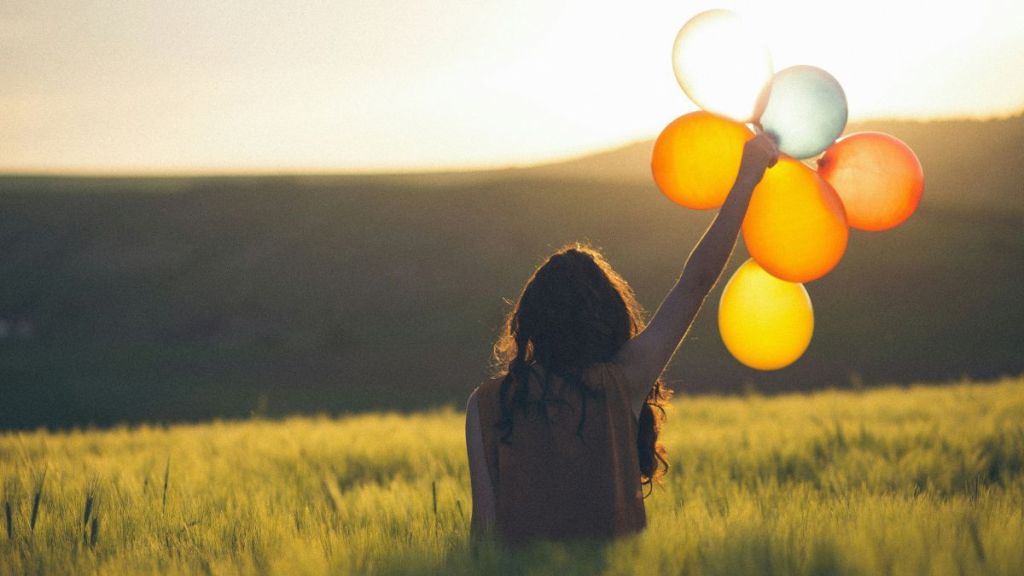 A woman holding a cluster of balloons outdoors.